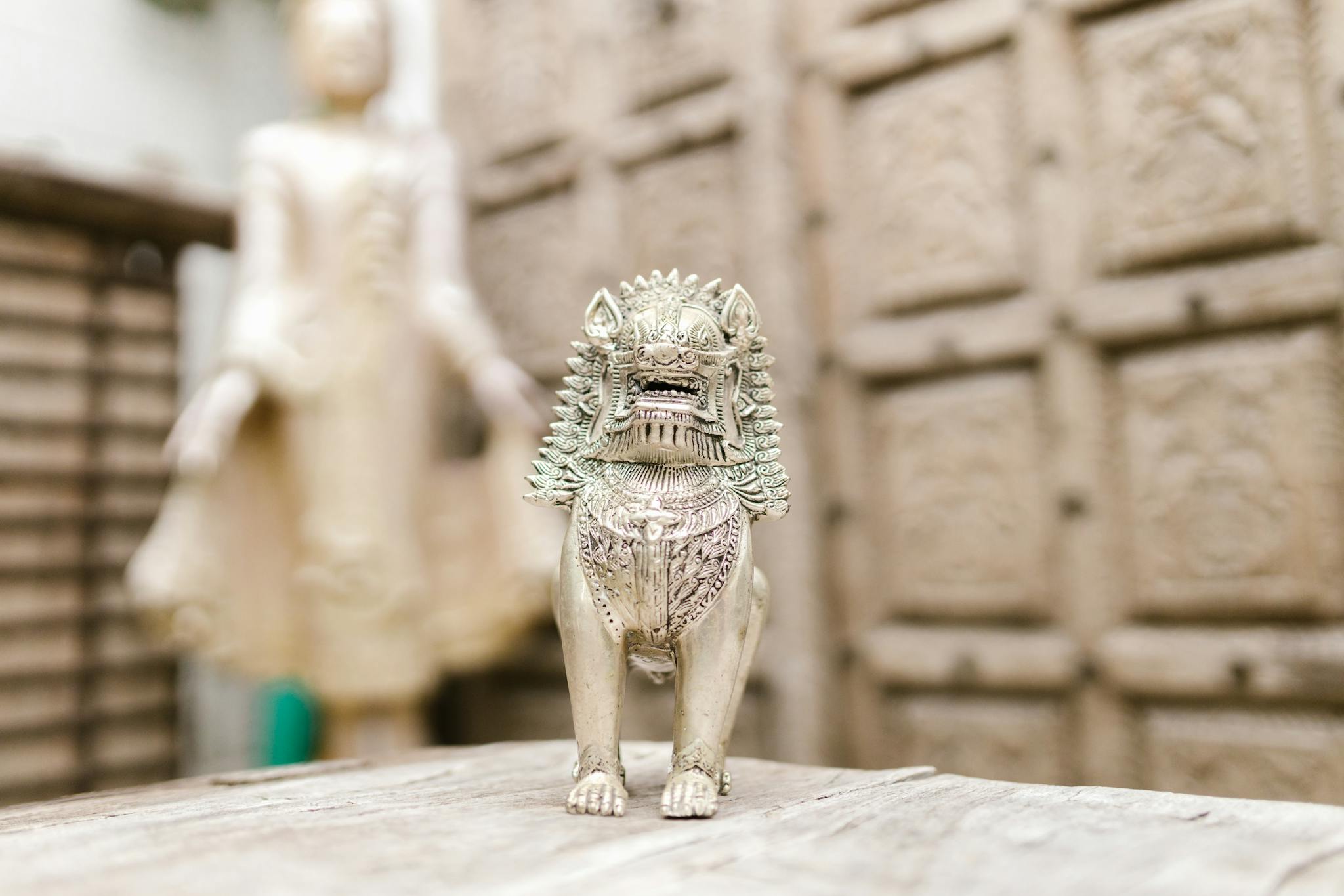 A detailed carved lion statue with traditional Buddhist art influence, set indoors.